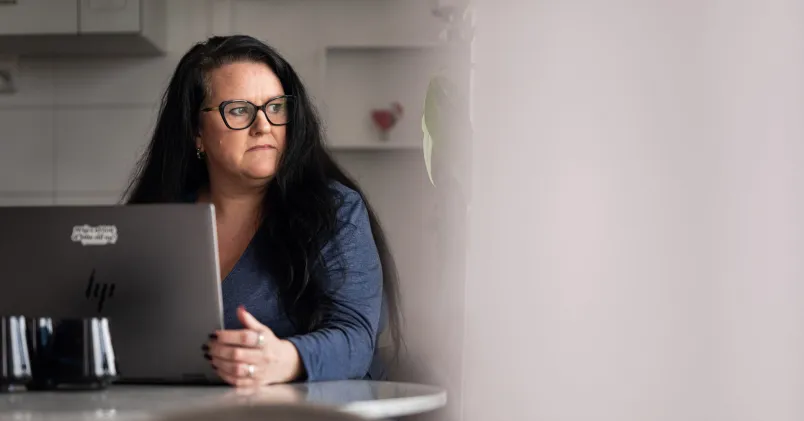 Christina Bundy i glasögon sitter vid dator i hemmamiljö; illustrerar artikel om ekonomisk utsatthet och långtidsarbetslöshet.