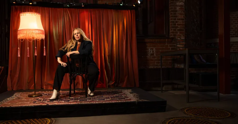 Petra Brylander, sitter på en stol på en liten teaterscen. 