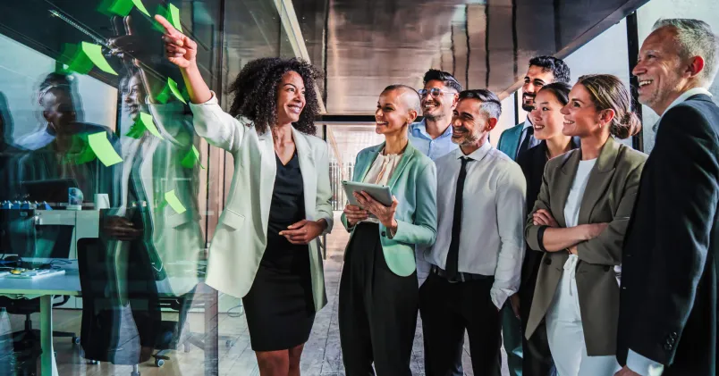 Grupp möts runt en chef som leder en genomgång och visar hur professionell klädsel förstärker ledarskap och arbetskommunikation.