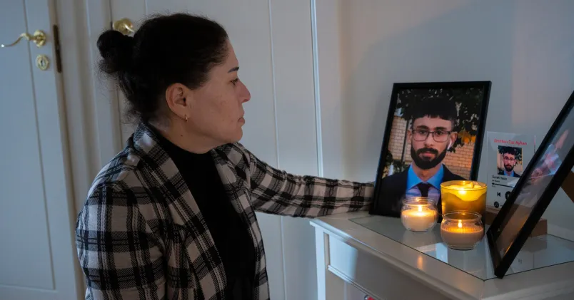 Tülün Tas tänder ett ljus intill ett fotografi av sin son.