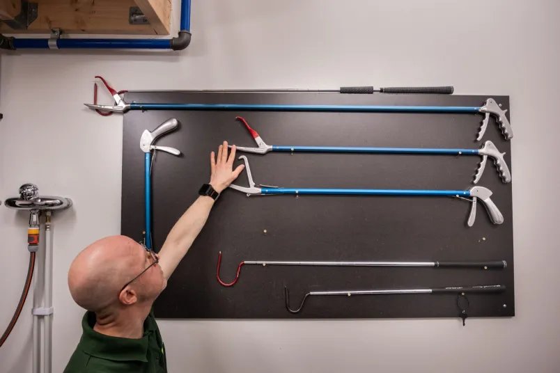 Eric Sundman står framför en vägg med olika verktyg som tänger och krokar.