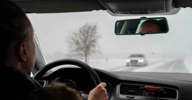 Kvinna kör bil på vintern. 