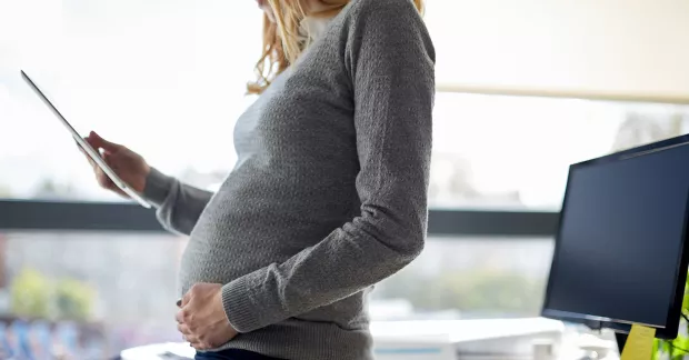 Kvinna med tidig gravidmage vid skrivbord.