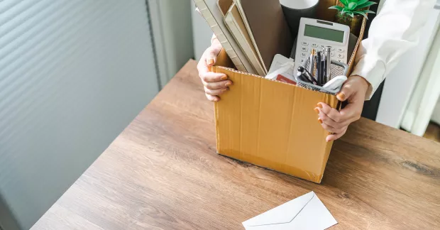 Kvinna packar ihop tillhörigheter från kontor i en kartong.