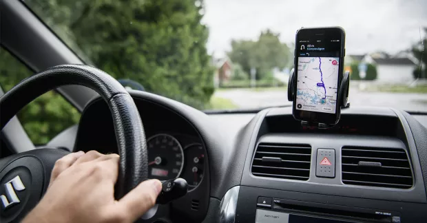 Person åker i bil med gps i mobilen.