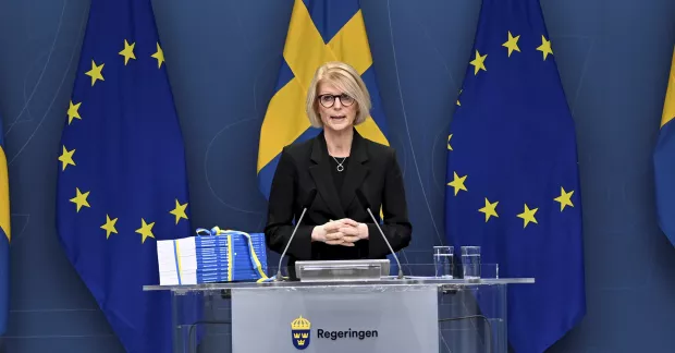 Elisabeth Svantesson under presskonferens med budgeten framför sig på podium.