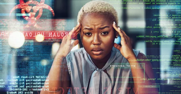 En kvinna vid en dator håller för öronen och ser trött ut. 