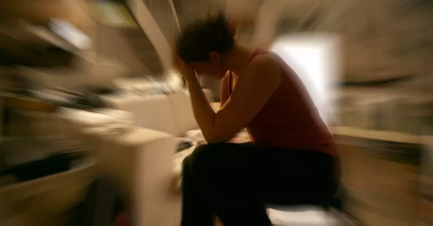 Suddig bild på stressad kvinna med huvudet i händerna. 