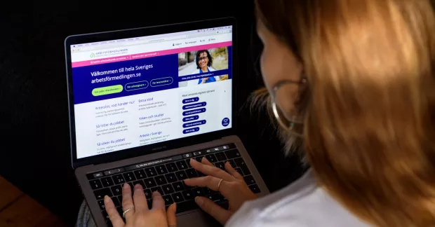 Ung kvinna vid en bärbar dator, söker arbete på Platsbanken. 