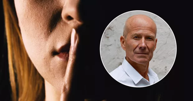 En kvinna som håller sitt finger framför munnen