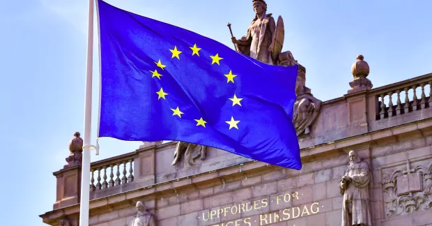 EU-flagga utanför riksdagen inför EU-valet. Partierna röster olika om den svenska modellen, visar Kollegas genomgång. 