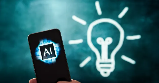 En telefon där skärmen visar AI bredvid en tecknad glödlampa.