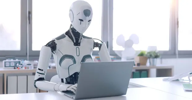 En humanoid robot som sitter vid en dator.