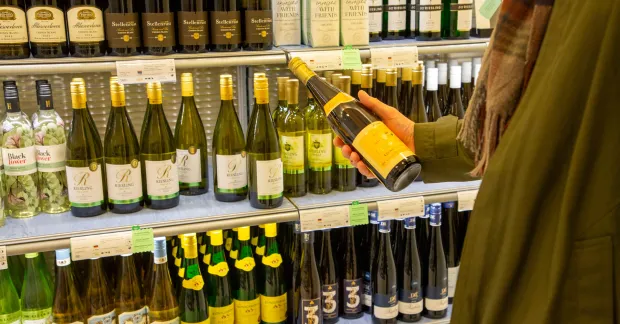 Ingen strejk på Systembolaget. På bilden en kund framför en hylla med vitvinsflaskor. 