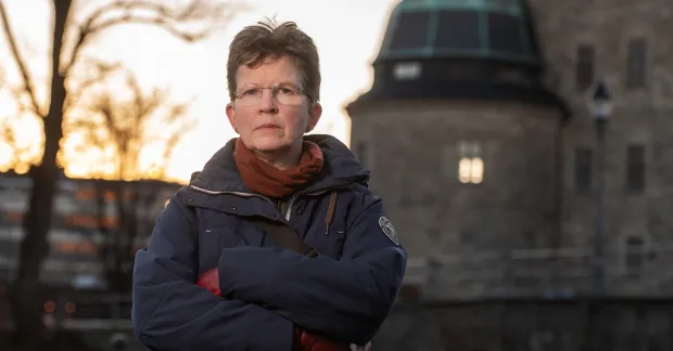 Sif Bjarnason står vid Örebro slott i skymning. Hon ser bestämd ut.