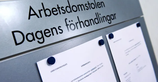 En skylt med texten "Arbetsdomstolen Dagens Förhandlingar" uppsatt på en vägg