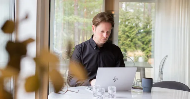 Jesper Ljung sitter vid ett bord med en laptop hemma i Åhus. Bilden kopplar till artikeln om att förlora jobbet och hitta en ny yrkesväg.