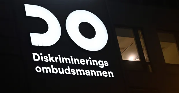 DO-logotyp och texten “Diskrimineringsombudsmannen” upplyst mot en mörk bakgrund.
