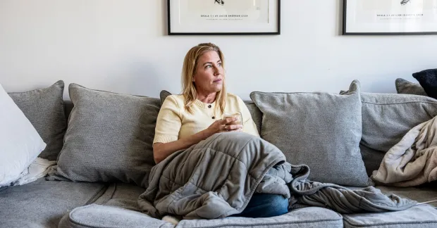 Hemmiljö med Jeanette Lilja i soffa och filt. Illustrerar situationen när barnet blir hemmasittare och vardagen stannar hemma.