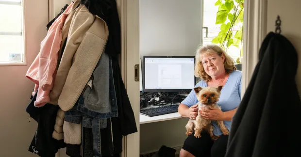 Kvinna med hund i knät framför dator