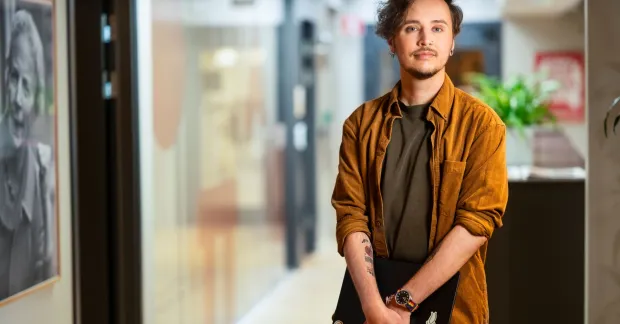 Christoffer Strokirk står på RFSU:s kontor med en dator i händerna.
