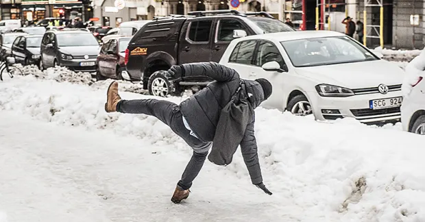 Person halkar på isigt underlag i stadsmiljö – fallolyckor är vanligaste arbetsskadan bland tjänstemän.