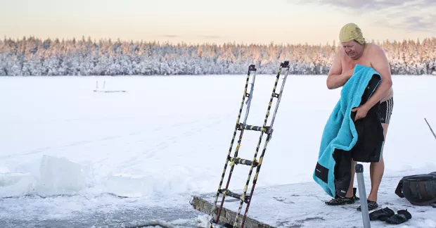 Jarkko Enqvist torkar sig med handduk bredvid isvak. 