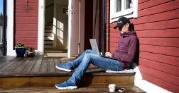 Man sitter på altan med dator i knät.