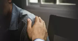 Man lägger handen på annan mans axel.