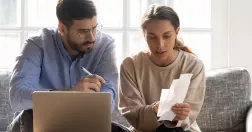 Man och kvinna sitter och tittar på kvitton vid datorn.
