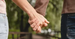Par håller varandra i handen och promenerar i en park.