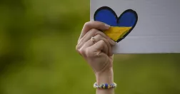 Kvinna håller upp skylt med hjärta i Ukrainas färger.