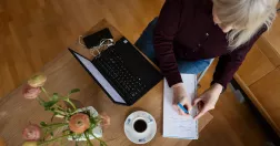 Kvinna sitter och jobbar hemma vid laptop.