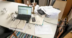 Skrivbord i hemmiljö. Fyllt med jobbpapper, en bärbar dator och en mobiltelefon. 
