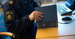 Uniformerad polis vid ett skrivbord med dator. Läser en lagbok.