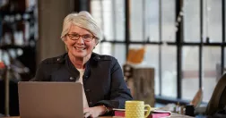 Glad kvinna vid laptop.