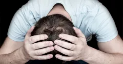 Man med händerna på sitt nedböjda huvud.