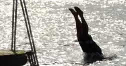 Person dyker i vatten från brygga.