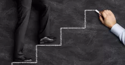 Man går upp för trappa som är ritad på svart tavla.