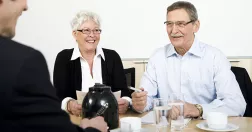 Personer i pensionsålder runt ett fikabord.