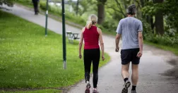 En kvinna och en man är ute och promenerar i en park.