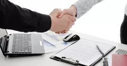 Två personer tar i hand över skrivbord.