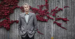 Mats Alvesson framför en betongvägg med vildvin.