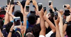 Grupp av människor tar selfies med mobiltelefoner.