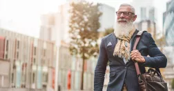 Man i pensionsålder promenerar i stadsmiljö.