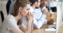 Kvinna på kontor lutar huvudet mot sin knutna händer.