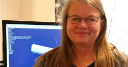 Susanne Karlsson framför sin skärm och arbetsplats.