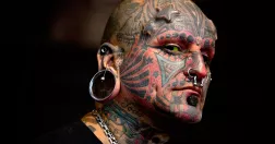Man med tatueringar över hela ansiktet och halsen.