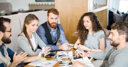 Unga människor sitter och jobbar runt ett bord.