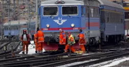 Järnvägsarbetare på spår framför stillastående SJ-tåg.